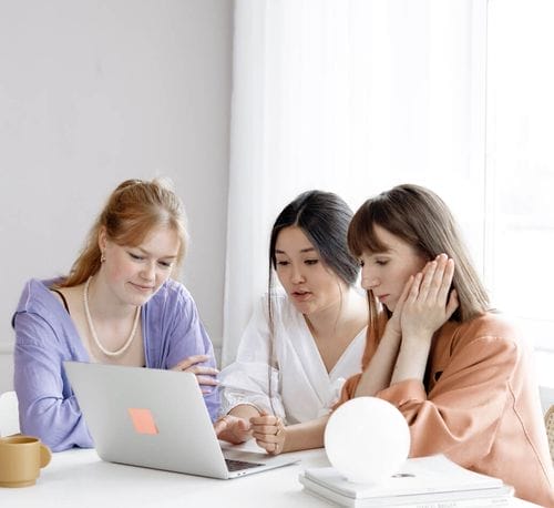 A group of women looking at a laptop.